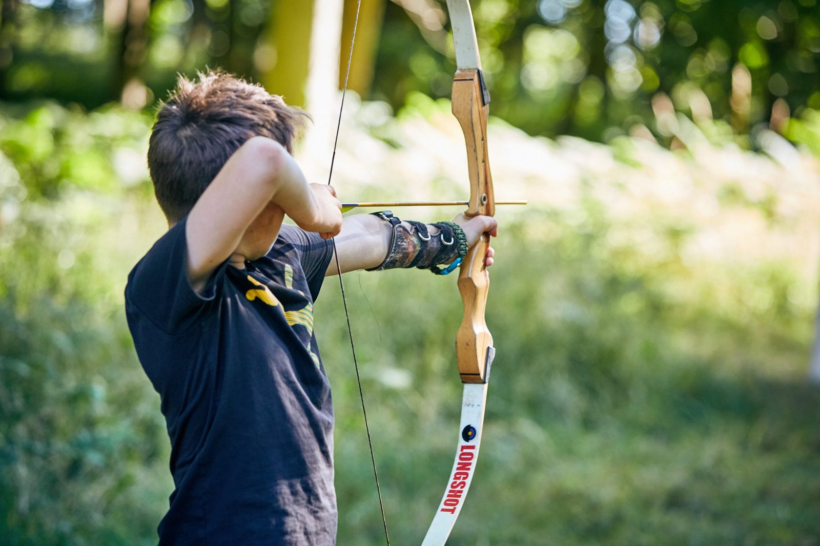 Year 7 student drawing a bow during archery on a bushcraft school trip